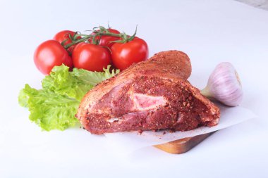 Çiğ domuz knuckle ve sebze, sarımsak, domates baharat ve marul yaprakları bir kesme tahtası üzerinde. Seçici odak. Hazır yemek pişirmek için.