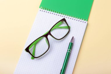 İş amaçlı aksesuarları üstünde okul sırası: Not Defteri, günlük, dolma kalem, gözlük. Makro bulanıklık ve yumuşak odak ile.