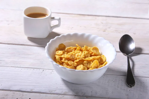 Καλαμπόκι νιφάδες δημητριακών με το γάλα σε ένα μπολ και καπάκι με καφέ espresso. Πρωινό το πρωί. — Φωτογραφία Αρχείου