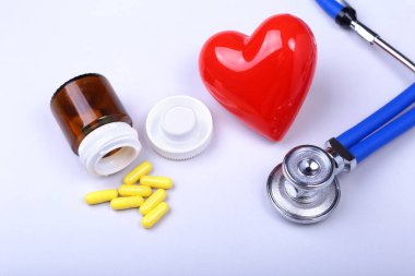 Stetoskop, kırmızı kalp ve metin için yer ile beyaz tabloda çeşitli hap.