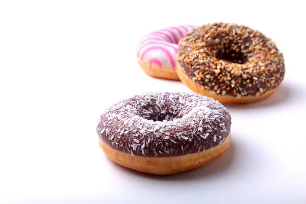 Assorted doughnuts in the glaze, colorful sprinkles and nuts on a white background. — Stock Photo, Image