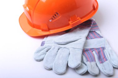 Beyaz bir arka planda turuncu zor şapka, gözlük ve emanet eldiven.