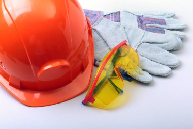 Beyaz bir arka planda turuncu zor şapka, gözlük ve emanet eldiven.