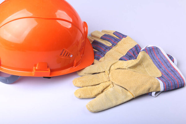 Orange hard hat, goggles and safety gloves on a white background.