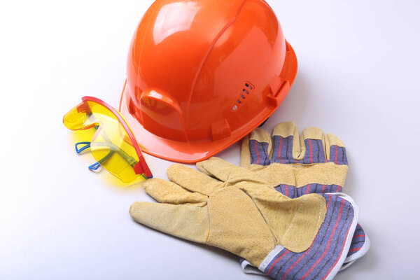 Оранжевая жесткая шляпа, когти и защитные перчатки на белом фоне
.