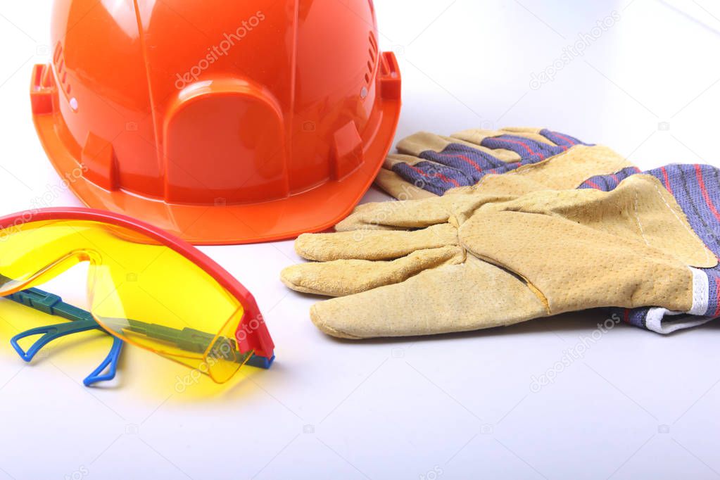 Orange hard hat, goggles and safety gloves on a white background.