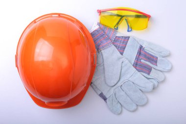 Beyaz bir arka planda turuncu zor şapka, gözlük ve emanet eldiven.