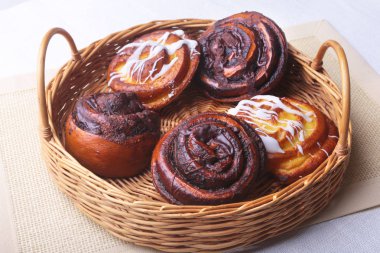 Ev yapımı taze pişmiş tatlı çörek ya da tatlı tarçın ile bir hasır sepet rulo.