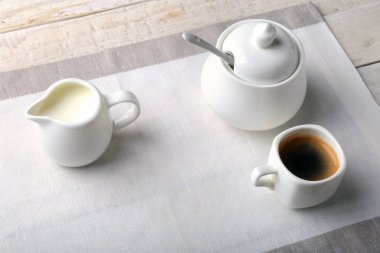 Bir fincan sıcak kahve espresso, kahve çekirdekleri, sürahi süt ve şeker kopya alanı için beyaz arka plan üzerine bir kase. Kahve kavramı.
