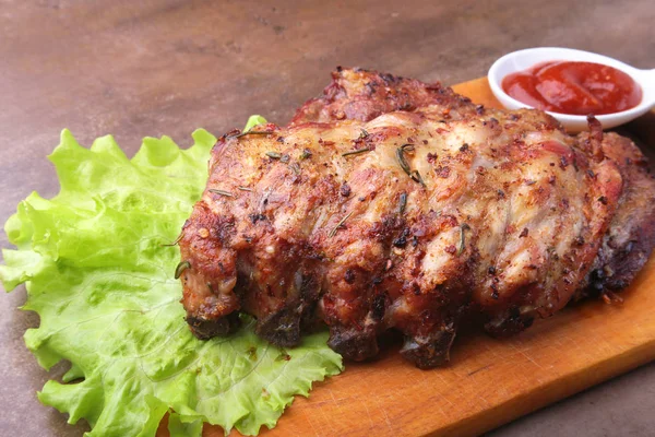 Iga panggang panggang dengan daun selada, cabai pedas dan saus di papan potong kayu . — Stok Foto