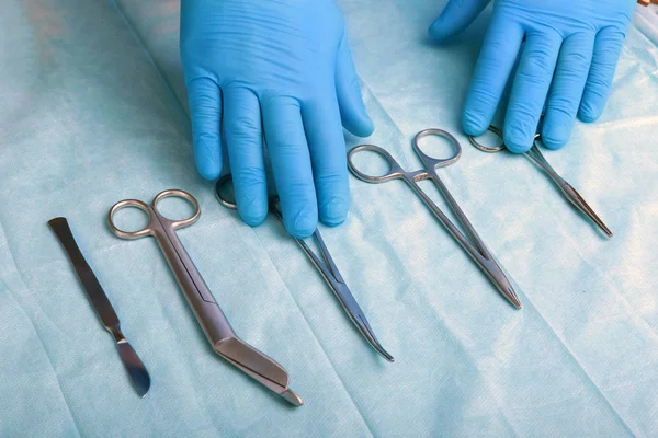 Detalle plano de instrumentos de cirugía esterilizada con una mano agarrando una herramienta  , — Foto de Stock