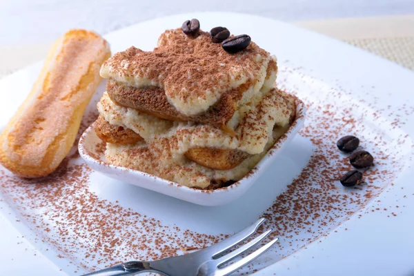 Pedaço de bolo de tiramisu caseiro apetitoso no prato de perto . — Fotografia de Stock