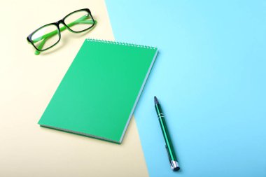 İş amaçlı aksesuarları üstünde okul sırası: Not Defteri, günlük, dolma kalem, gözlük. Makro bulanıklık ve yumuşak odak ile.