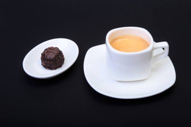 Klasik espresso kahve ve pralin siyah arka plan üzerine beyaz fincan.