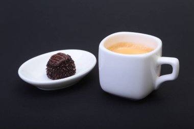 Klasik espresso kahve ve pralin siyah arka plan üzerine beyaz fincan.