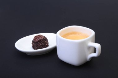 Klasik espresso kahve ve pralin siyah arka plan üzerine beyaz fincan.