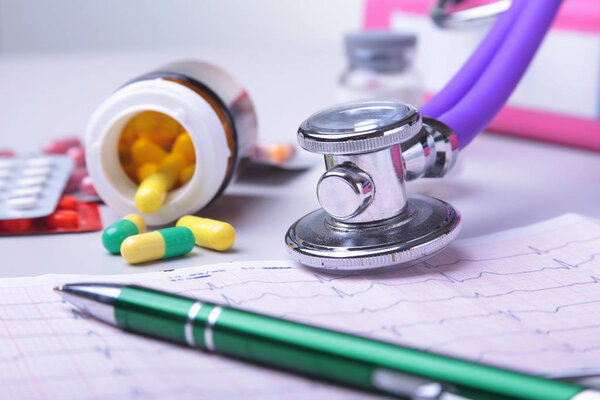 Close-up stethoscope lying on RX prescription with assorted pills. Healthy life or insurance concept.