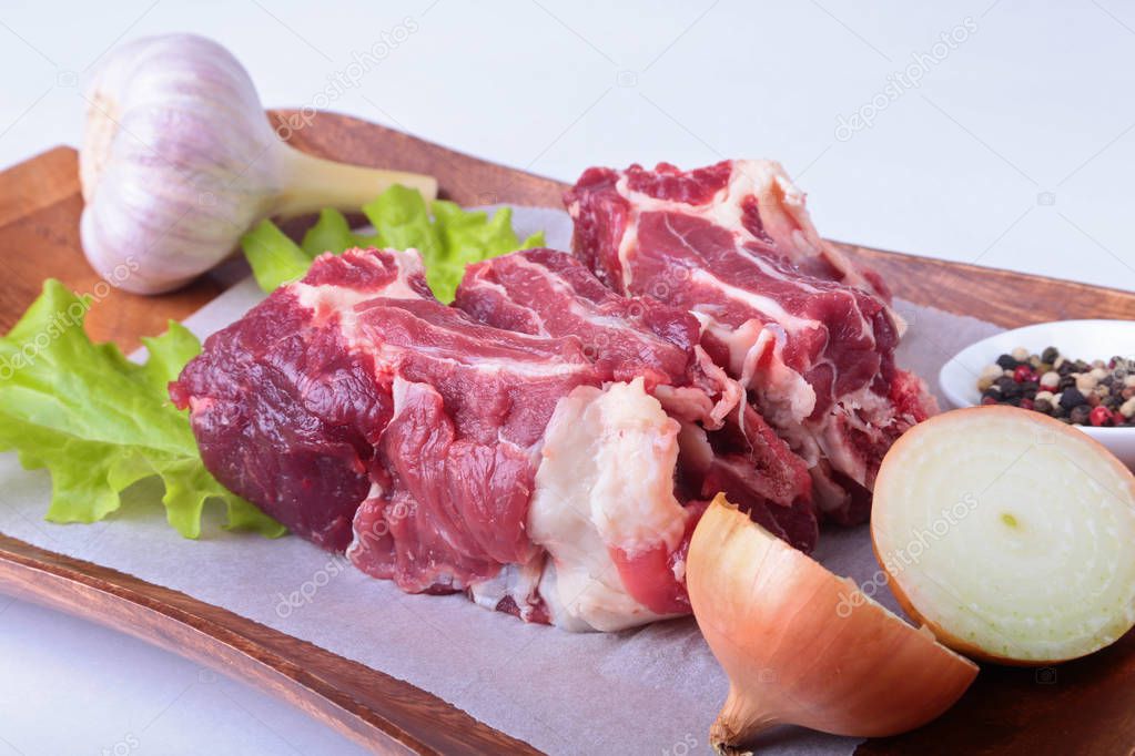 Raw beef edges, lettuce leaf, garlic, pepper grinder and spices on wooden desk isolated on white background from above and copy space. ready for cooking.