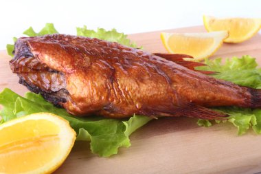 Füme balık ve beyaz arka plan üzerinde izole tahta kesme tahta üzerinde yeşil marul yaprakları limon.