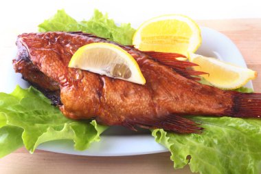 Füme balık ve beyaz arka plan üzerinde izole tahta kesme tahta üzerinde yeşil marul yaprakları limon.