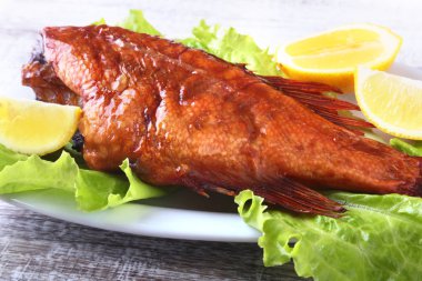 Füme balık ve beyaz arka plan üzerinde izole tahta kesme tahta üzerinde yeşil marul yaprakları limon.