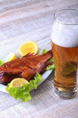Beyaz arka plan üzerinde izole bira ile balık ve limon yeşil marul yaprakları ahşap kesme tahtası ve cam üzerinde füme.
