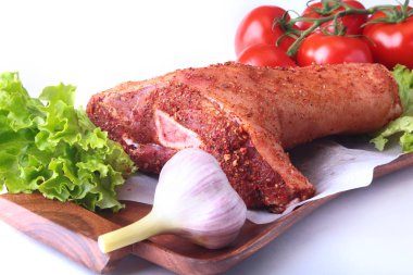 Çiğ domuz knuckle ve sebze, sarımsak, domates baharat ve marul yaprakları bir kesme tahtası üzerinde. Seçici odak. Hazır yemek pişirmek için.