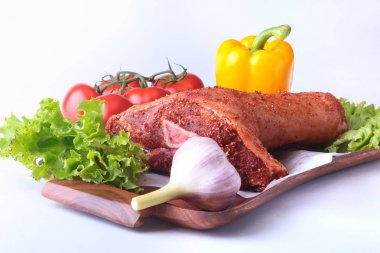 Çiğ domuz knuckle ve sebze, sarımsak, domates, dolmalık biber. baharat ve marul yaprakları bir kesme tahtası üzerinde. Seçici odak. Hazır yemek pişirmek için.