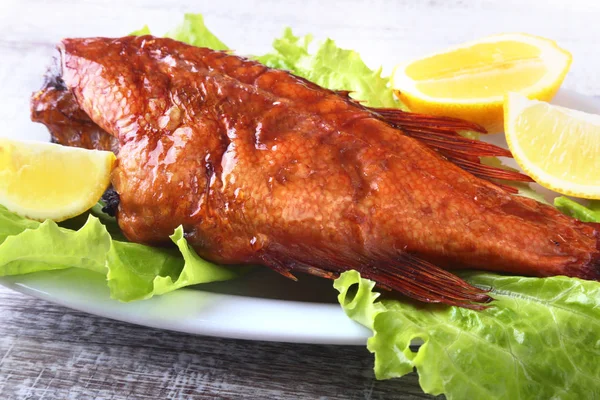 Füme balık ve beyaz arka plan üzerinde izole tahta kesme tahta üzerinde yeşil marul yaprakları limon.