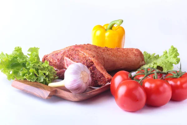 Çiğ domuz knuckle ve sebze, sarımsak, domates, dolmalık biber. baharat ve marul yaprakları bir kesme tahtası üzerinde. Seçici odak. Hazır yemek pişirmek için. — Stok fotoğraf