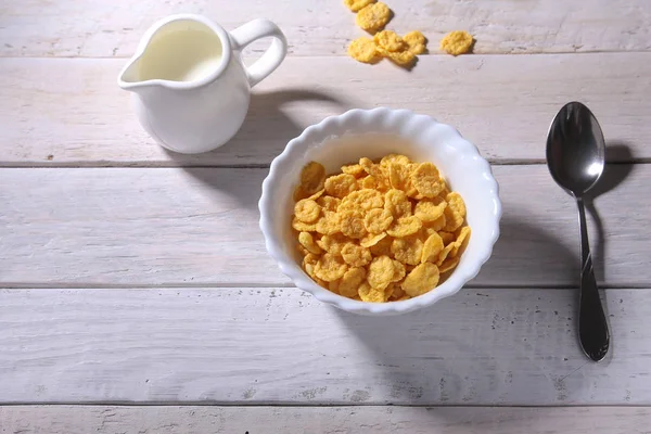 Copos de maíz cereales en un tazón y un vaso con leche. Desayuno por la mañana . — Foto de Stock