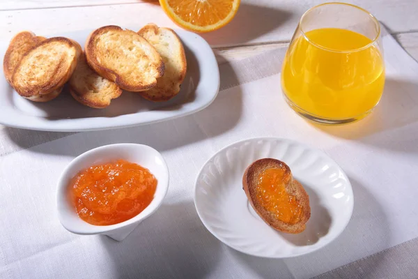 Desayuno por la mañana con mermelada de naranja en pan tostado y jugo en vaso . —  Fotos de Stock