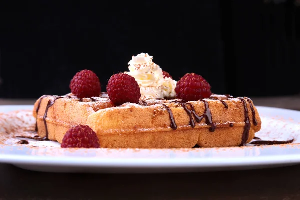 Fechar os waffles belgas caseiros com chantilly, molho de chocolate e framboesas no prato branco . — Fotografia de Stock
