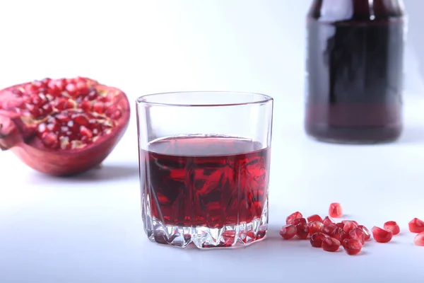 Glas med granatäpple juice granatäpplekärnor och vacker mogen granatäpple på vit bakgrund med plats för kopia utrymme. — Stockfoto