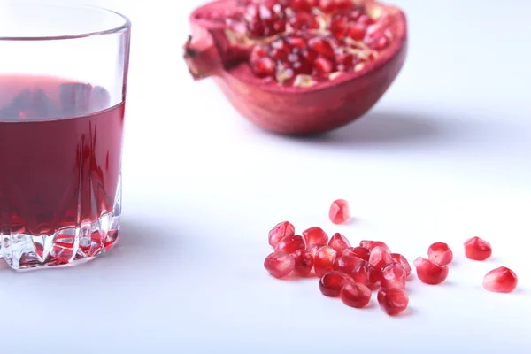 Glas med granatäpple juice granatäpplekärnor och vacker mogen granatäpple på vit bakgrund med plats för kopia utrymme. — Stockfoto