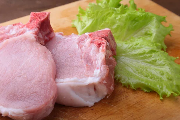 Raw chop on a rustic cutting board with salt, pepper and grinder for spices. для копирования места. Вид сверху . — стоковое фото