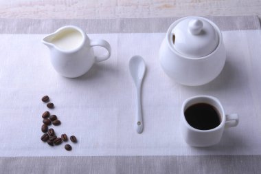 Bir fincan sıcak kahve espresso, kahve çekirdekleri, sürahi süt ve şeker kopya alanı için beyaz arka plan üzerine bir kase. Kahve kavramı.