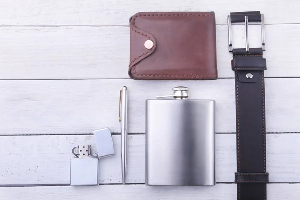 Gadgets en accessoires voor mannen op lichte houten achtergrond. Modieuze mannen s belt, portemonnee, lichter, RVS heupfles en pen. — Stockfoto