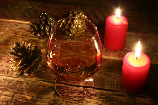 Candele natalizie e vetro con cognac o whisky su fondo legno. Addobbi natalizi . — Foto Stock