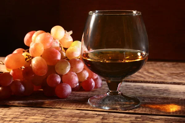 Konjak eller Brandy i ett glas och färska druvor, stilleben i rustik stil, vintage trä bakgrund, selektivt fokus. — Stockfoto