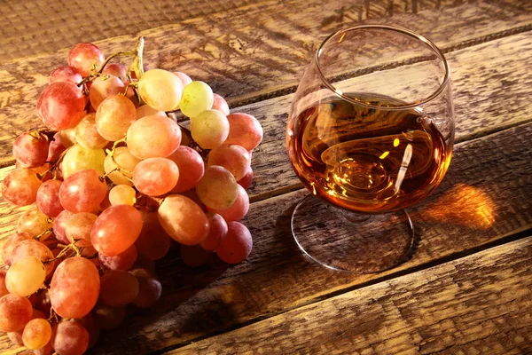 Konjak eller Brandy i ett glas och färska druvor, stilleben i rustik stil, vintage trä bakgrund, selektivt fokus. — Stockfoto
