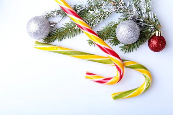 Weihnachtsbaum, Geschenkbox, Lutscher und bunte Kugeln auf weißem Hintergrund. Kopierraum. — Stockfoto