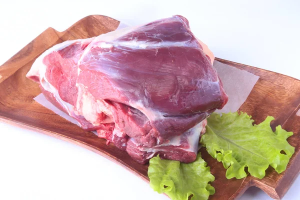 Rått nötkött skaft och salladsblad på trä skrivbord isolerade på vit bakgrund från ovan och kopiera utrymme. redo för matlagning. — Stockfoto