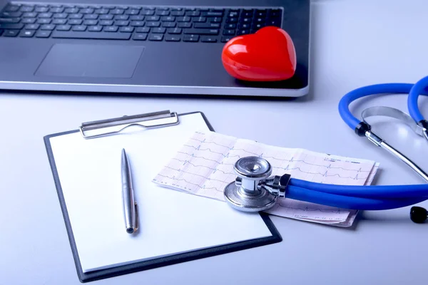 Lugar de trabajo del médico con portátil, estetoscopio, corazón rojo y prescripción RX en la mesa blanca. vista superior . — Foto de Stock