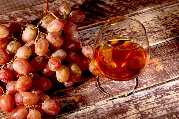 Konjak eller Brandy i ett glas och färska druvor, stilleben i rustik stil, vintage trä bakgrund, selektivt fokus. — Stockfoto