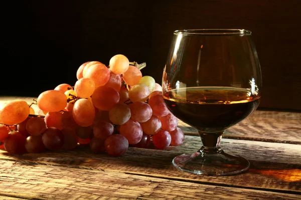 Koniaku lub Brandy w szklance i świeżych winogron, nadal życia w stylu rustykalnym, vintage drewniane tła, Selektywny fokus. — Zdjęcie stockowe