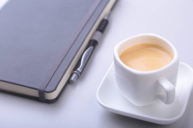 güzel kokulu espresso kahve, siyah şık dizüstü ve ofis masasında bir tükenmez kalem ile beyaz fincan