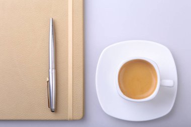 beyaz fincan kahve kokulu espresso, şık dizüstü ve ofis masasında bir tükenmez kalem. Üstten görünüm