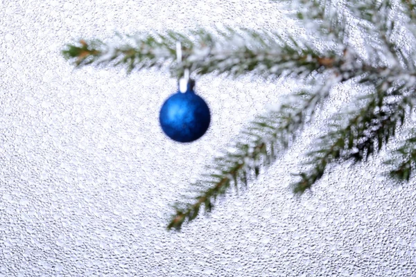 Wazig kerstboom en New Years bal met lint op ijs achtergrond. Decoratie voor prettige feestdagen. Kopiëren van ruimte. — Stockfoto