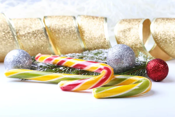 Árbol de Navidad y conos, bolas de colores de Año Nuevo con cinta, piruleta y caja de regalo sobre fondo blanco. Decoración para felices fiestas. Copiar espacio . — Foto de Stock